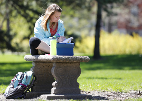 female student studying outdoors on a bench