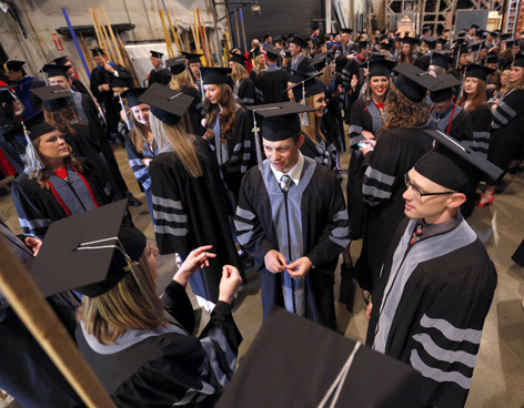 Graduates in academic gowns wait backstage