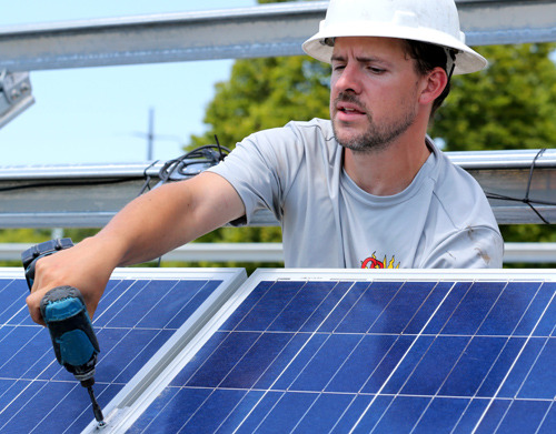 Worker attaches solar panel to rack