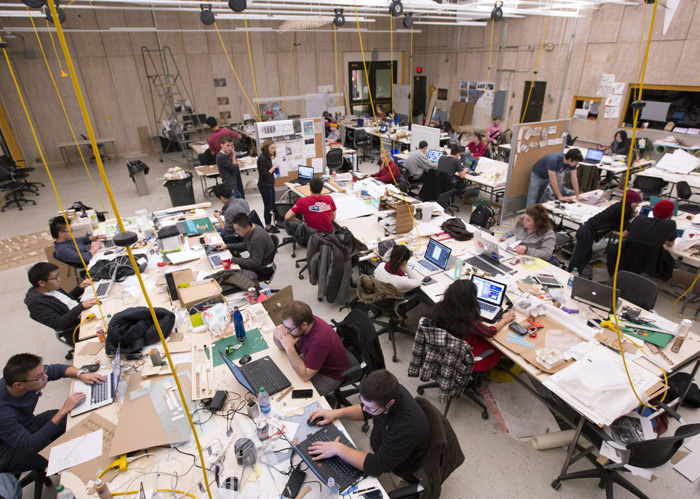 Large studio filled with students working at tables.