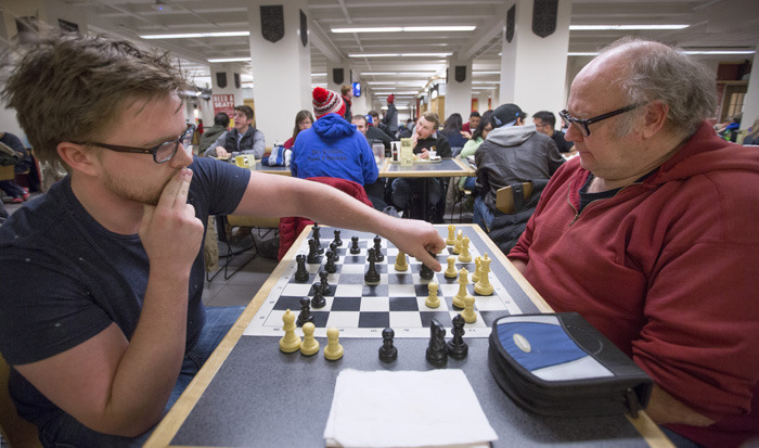 Two men play chess in the Memorial Union food court area