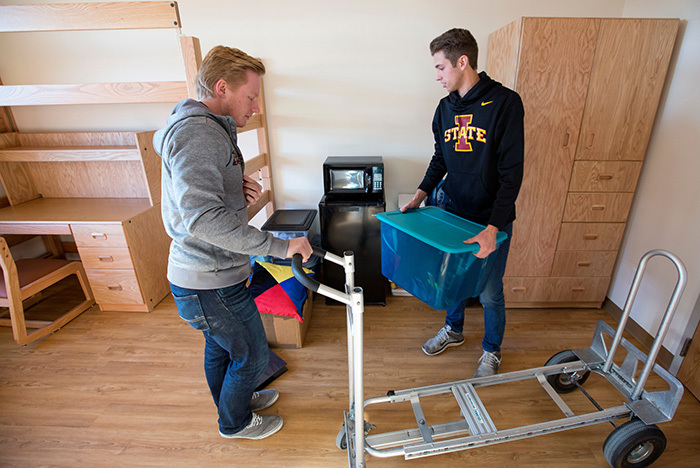 Two male students unload boxes from a moving cart