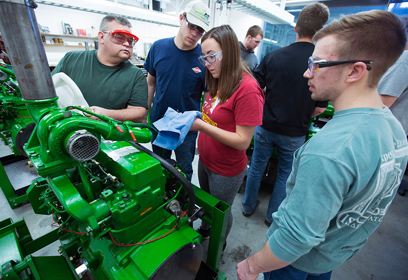 Four students work on a large tractor engine