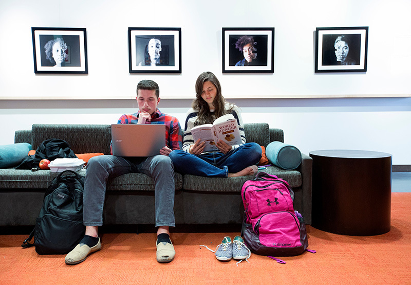 Male and female students study on a couch.
