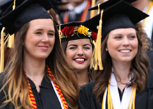 Three female students march in to their commencement ceremony