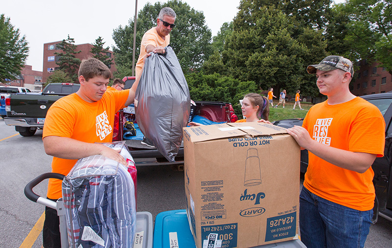 Student team in orange T-shirts unload a pickup truck