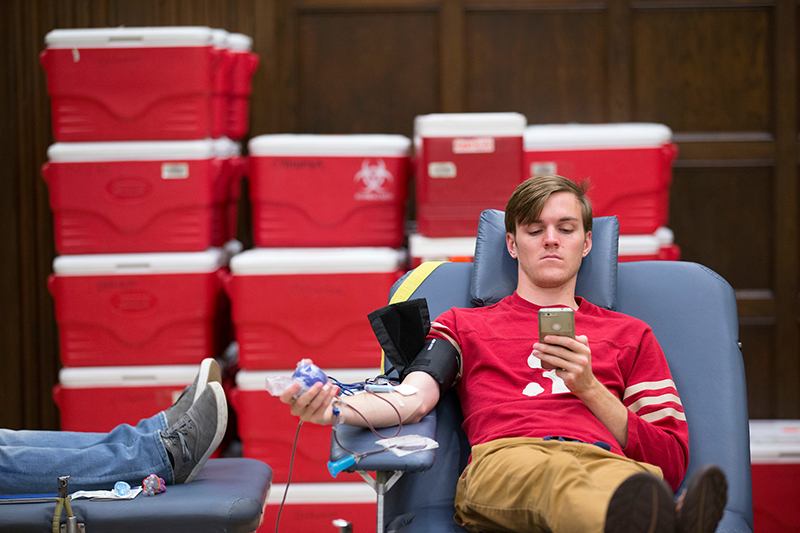 Seated male student is donating blood