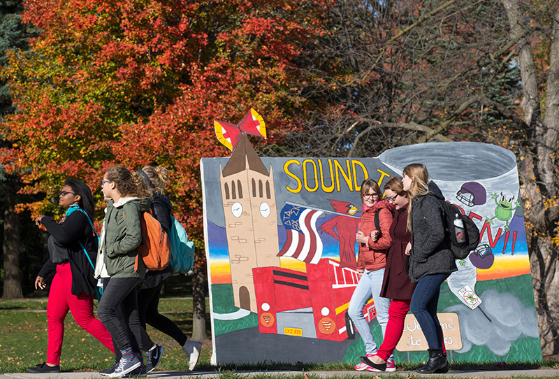 Female students pass a Homecoming banner on central campus