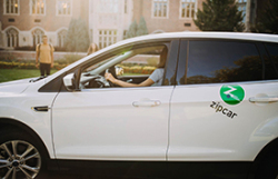 white sedan with Zipcar green dot logo on rear door