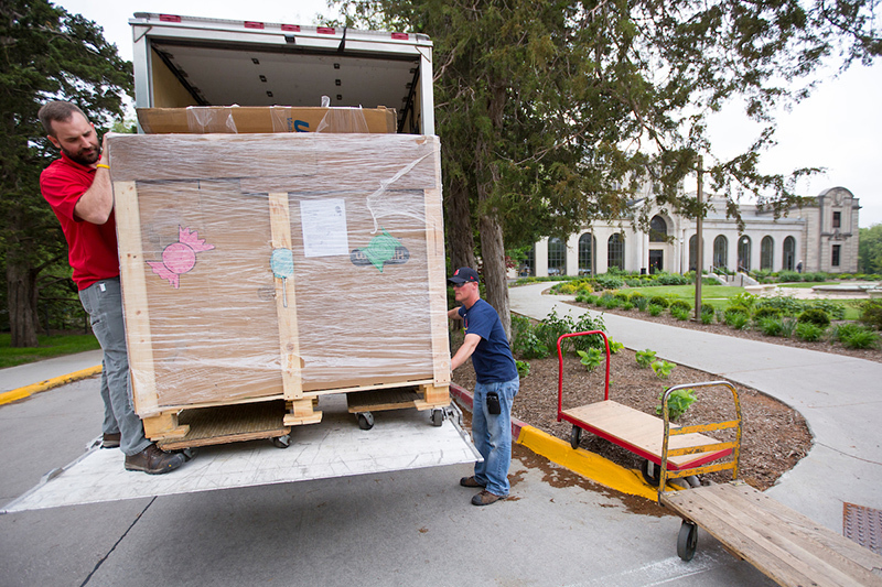 Two men unload a large crate from a box truck