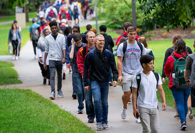 Students cross central campus on wet sidewalks.