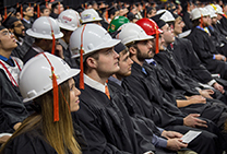 Construction engineering graduates attach tassels to hard hats