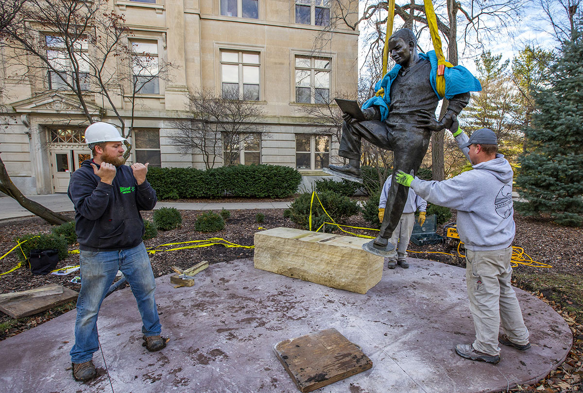 Crews lower the bronze Jack Trice sculpture to its new home nort