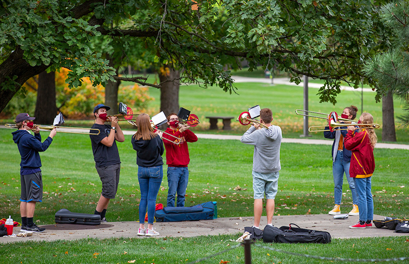 Marching band trombonists practice on central campus