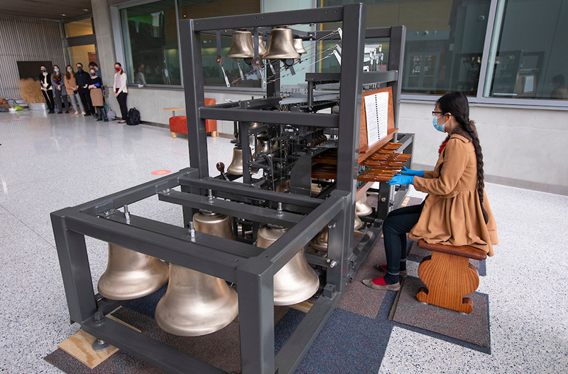 female student plays on carillon model