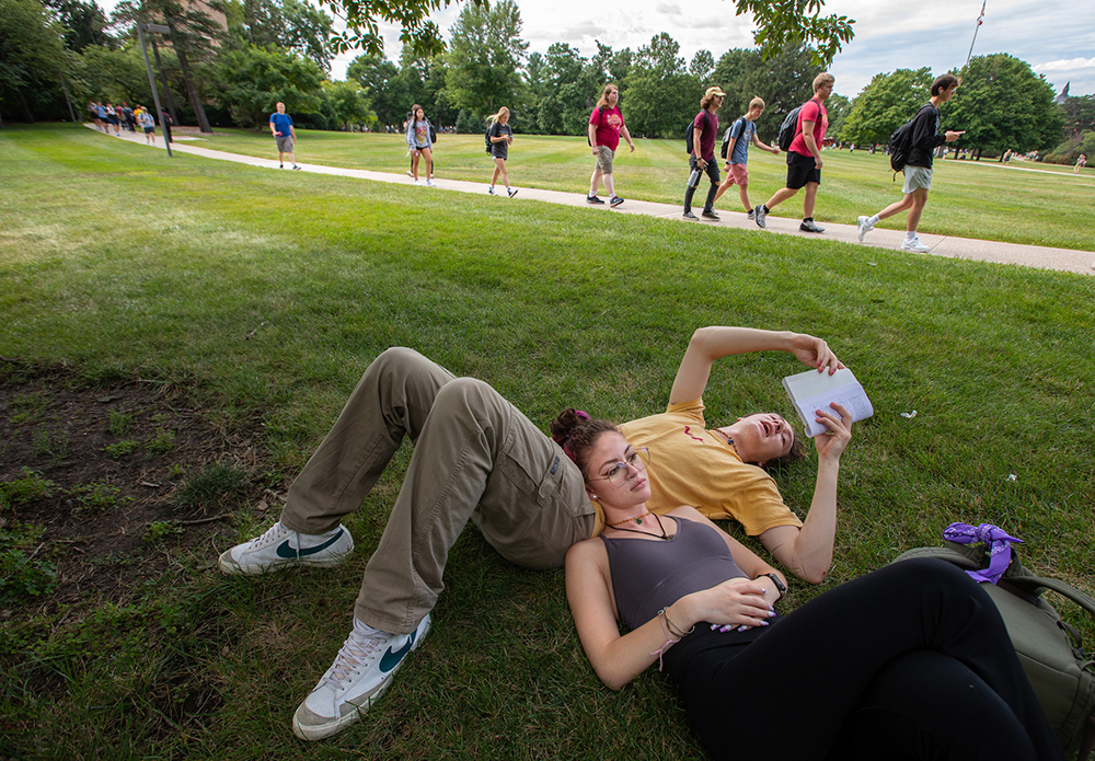 Male and female student studying on the central campus lawn