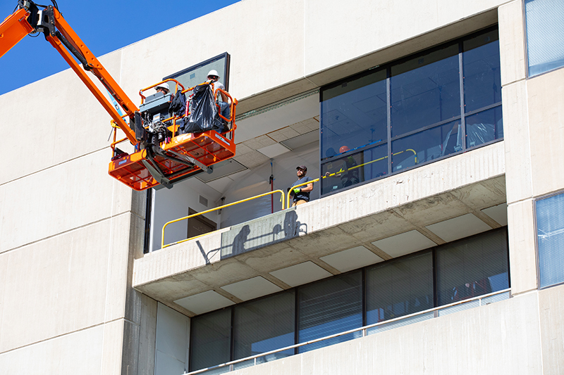 workers move window into fifth-floor position