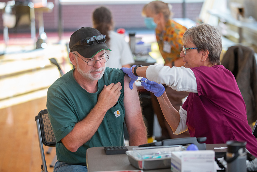 Roger Hintz receives flu shot in upper arm from Beverly Jones