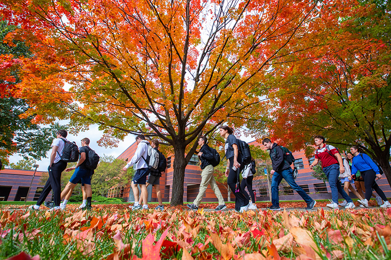 Students walk outside Black Engineering amid orange leaves