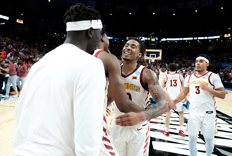 Male athletes in Cyclone white uniforms congratulate each other