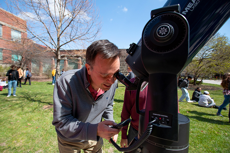 white male uses remote to adjust focus on telescope