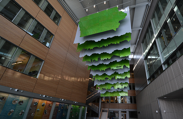 Metal layered (green and gray) sculpture hangs from atrium ceili