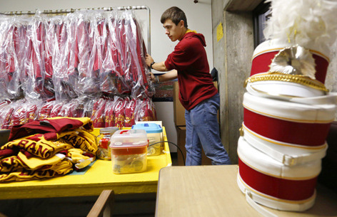 Male student moves rack of marching band uniforms