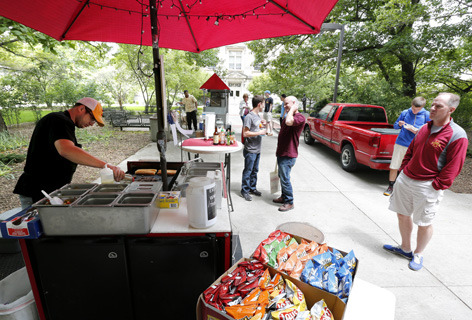 Man prepares cheesesteak sandwich at outdoor food cart