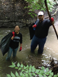 Two volunteers wade the creek, picking up trash