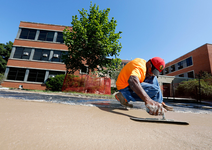 Worker smooths new sidewalk along Osborn Drive