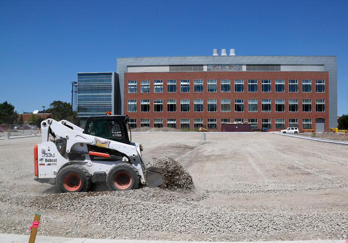 Worker in a skid loader prepares new parking area 