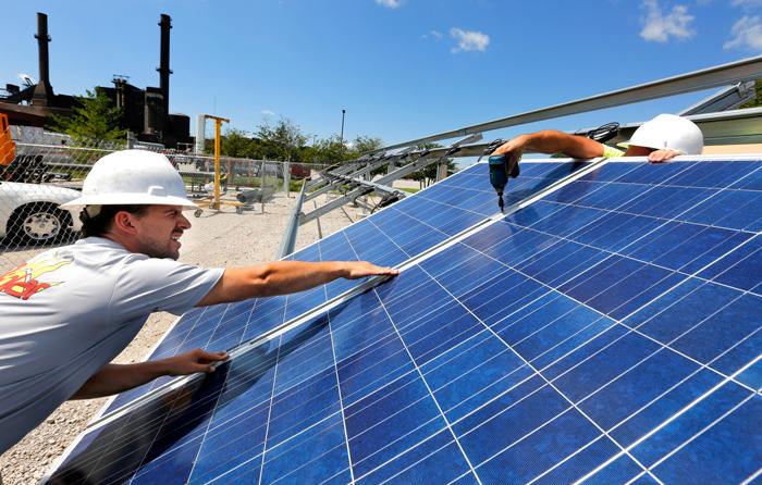 The Power Plant forms the backdrop as workers install new solar 