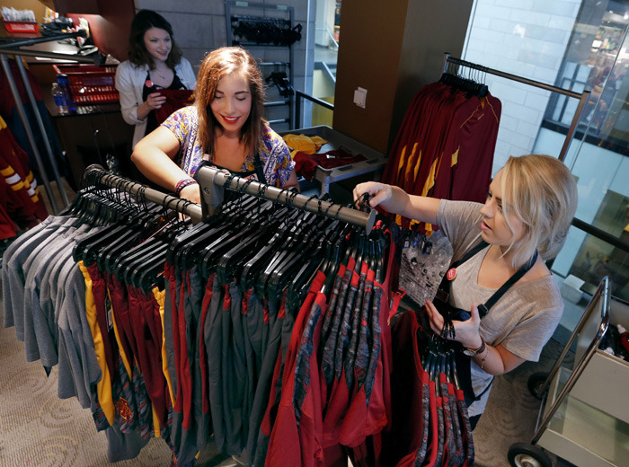 Three clerks fill racks with ISU clothing