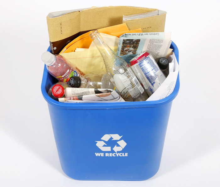 blue recycling bin filled with various papers and beverage conta