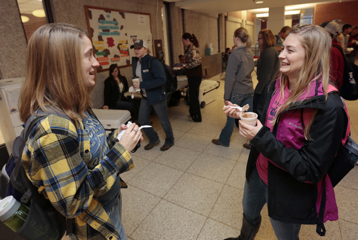 Two female students chat while eating from ice cream cups