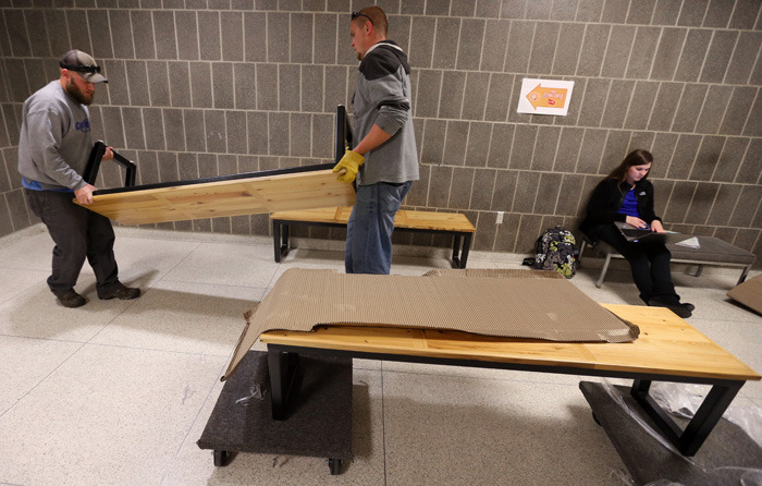 Two employees set up benches in a Carver Hall hallway