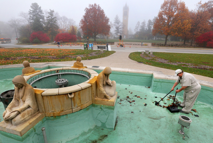 Employee sweeps leaves from the pool floor at the Fountain of th
