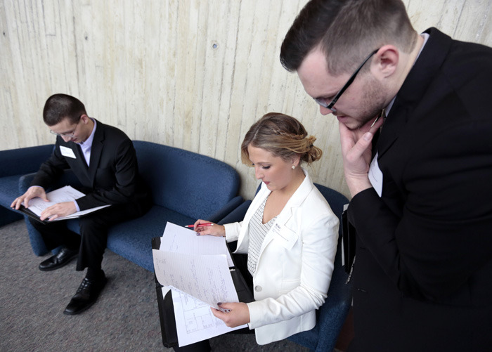 Two male and one female students consult their job fair notes.