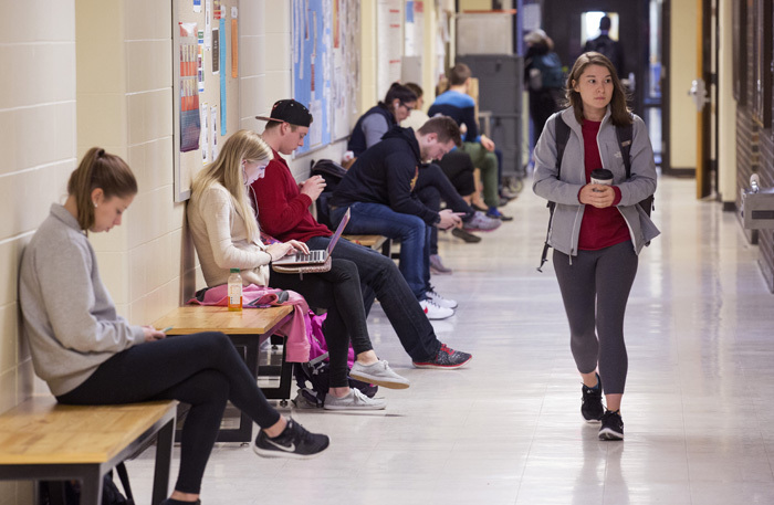 Students study on benches along a building hallway