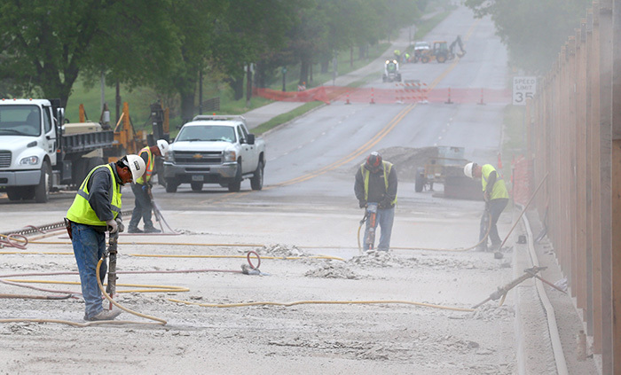 Workers use jack hammers to break up the bridge surface