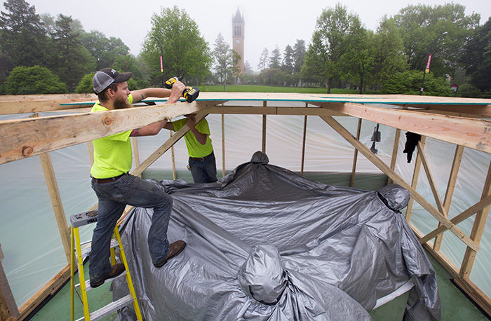 Workers build protective shed around outdoor sculpture