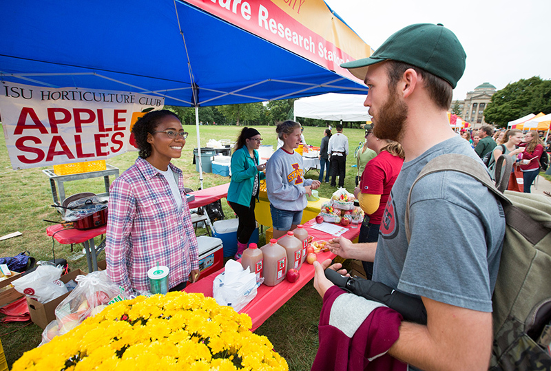 Two students visit at booth featuring apples and cider