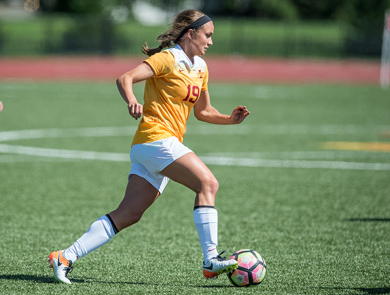 Female soccer player dribbles a soccer ball