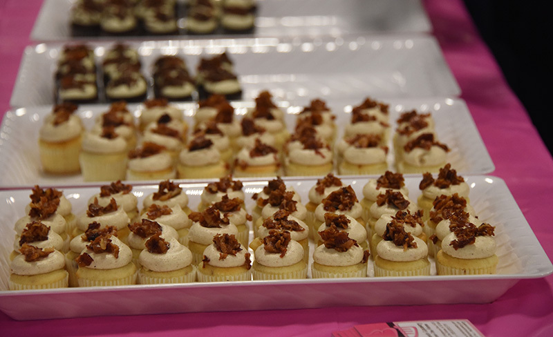 rows of frosted cupcakes topped with chopped bacon