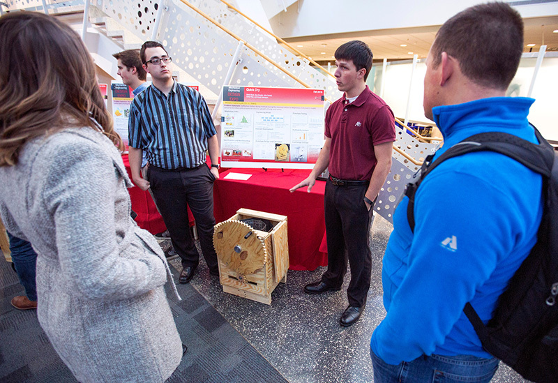 Two male students explain their clothes dryer to other students