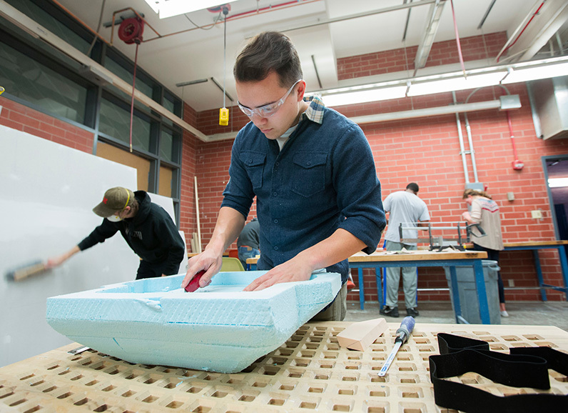 Male student cuts blue styrofoam form