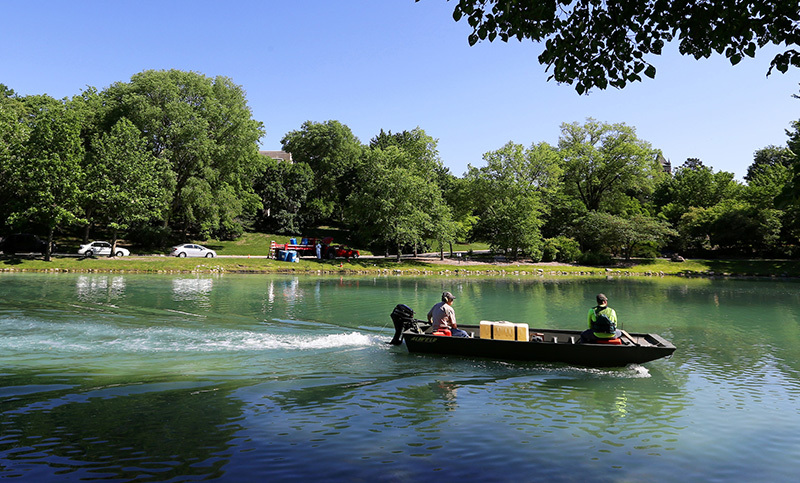 Flat boat on Lake LaVerne distributes liquid chemical into the w