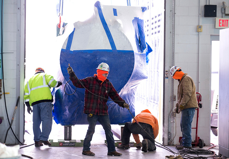 Crew members prepare to inflate the air floats beneath the cylin