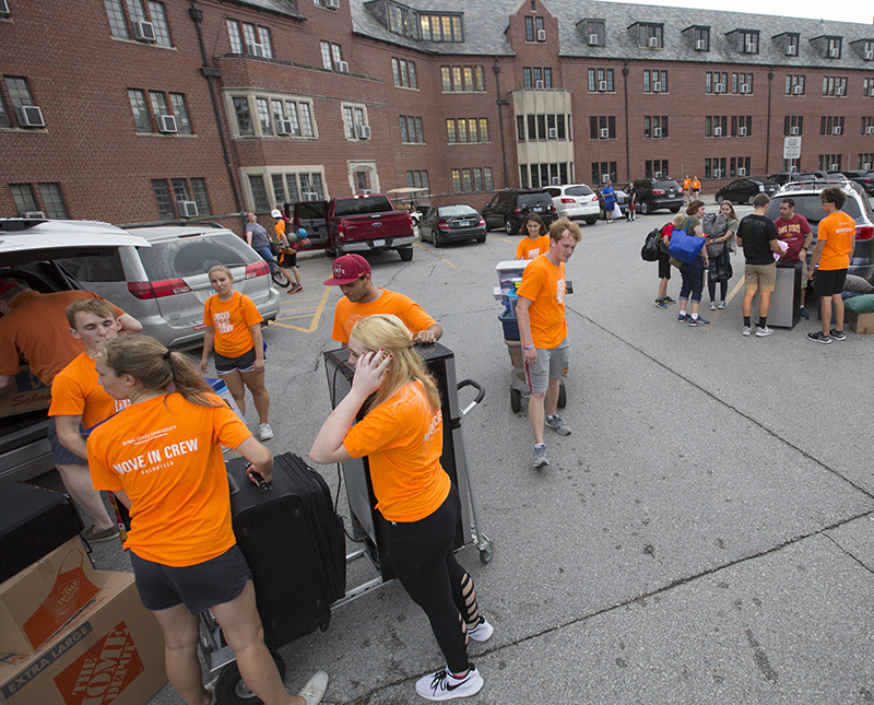 Student teams in orange shirts move new students into residence 