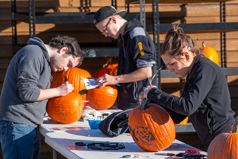 Three students stencil pumpkins